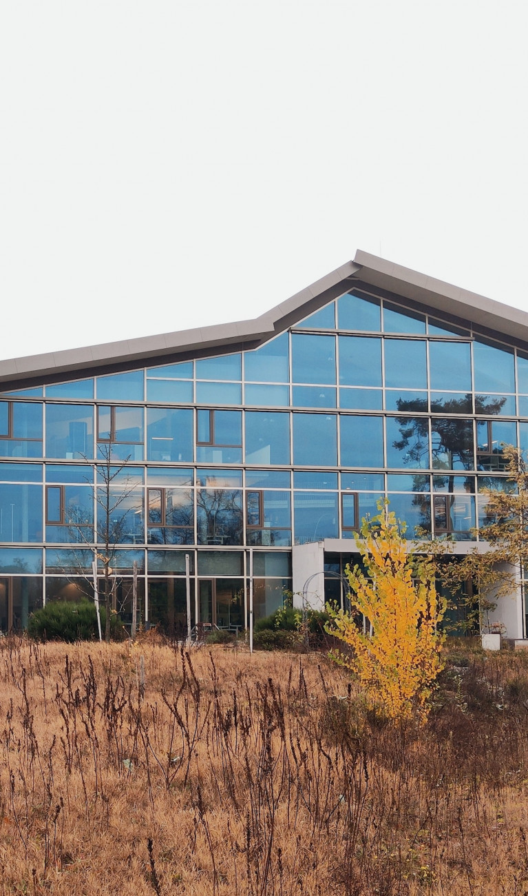 Ein modernes Haus mit viel Glas, ein Student steht davor