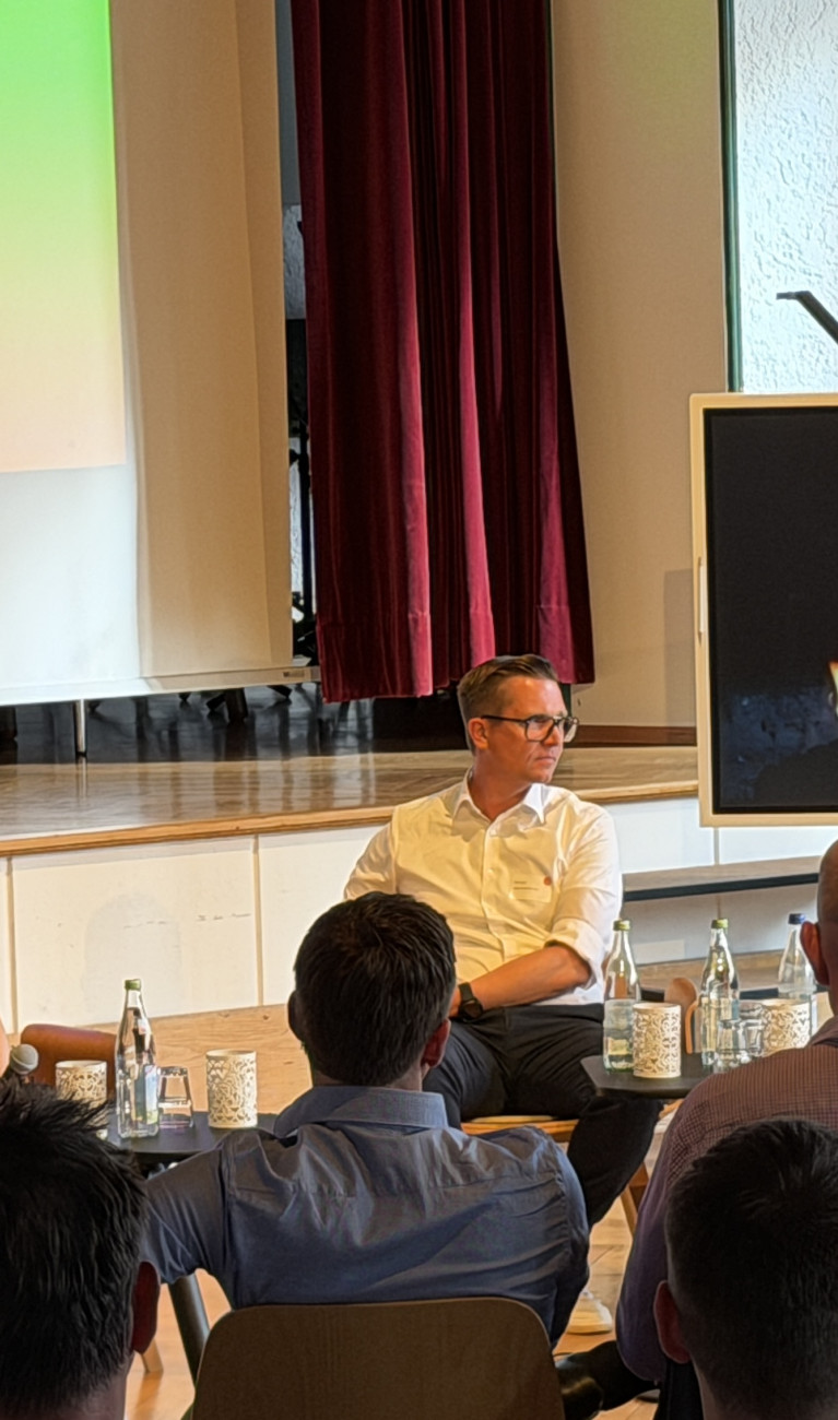 Personen sitzen bei einer Podiumsdiskussion vor Publikum