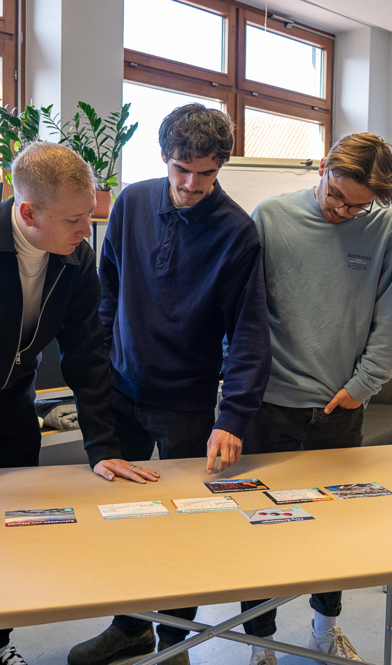 Personen stehen um einen Tisch herum und arbeiten interaktiv