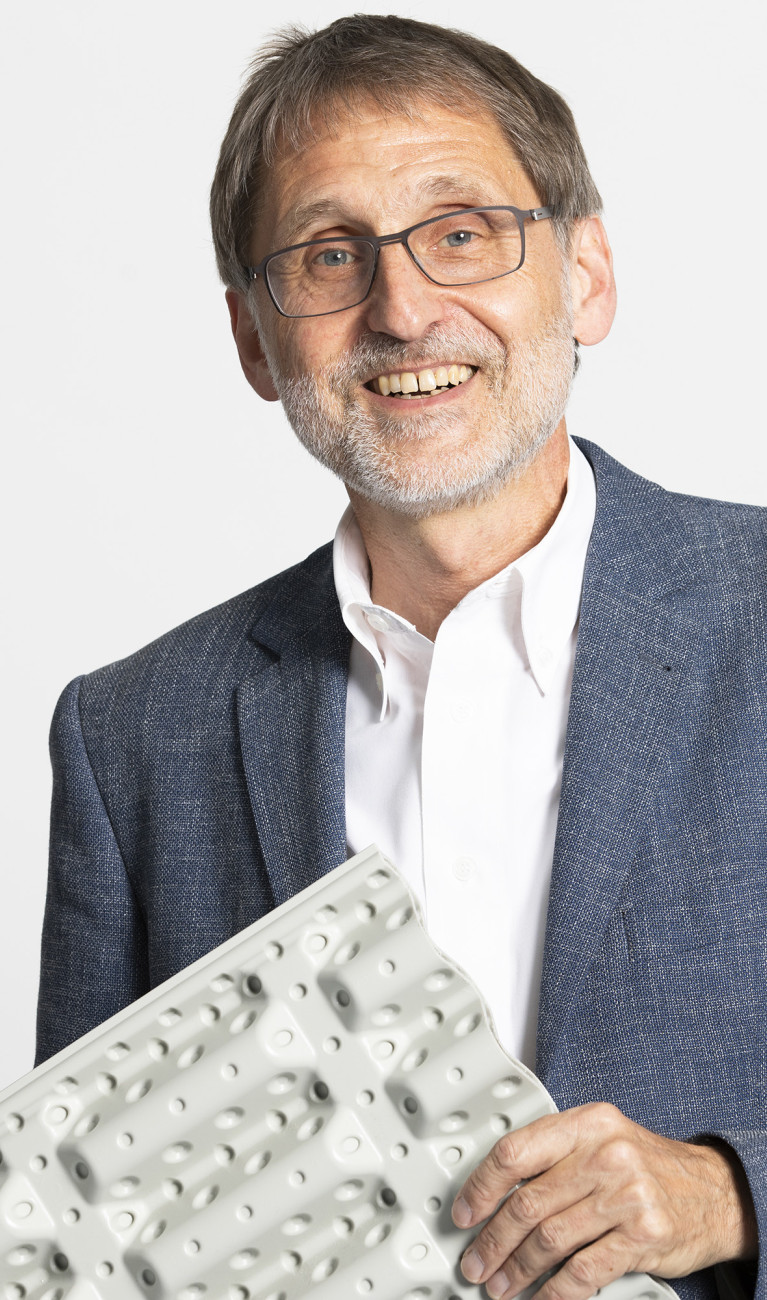 Ein Mann hält etwas in der Hand und lacht in die Kamera