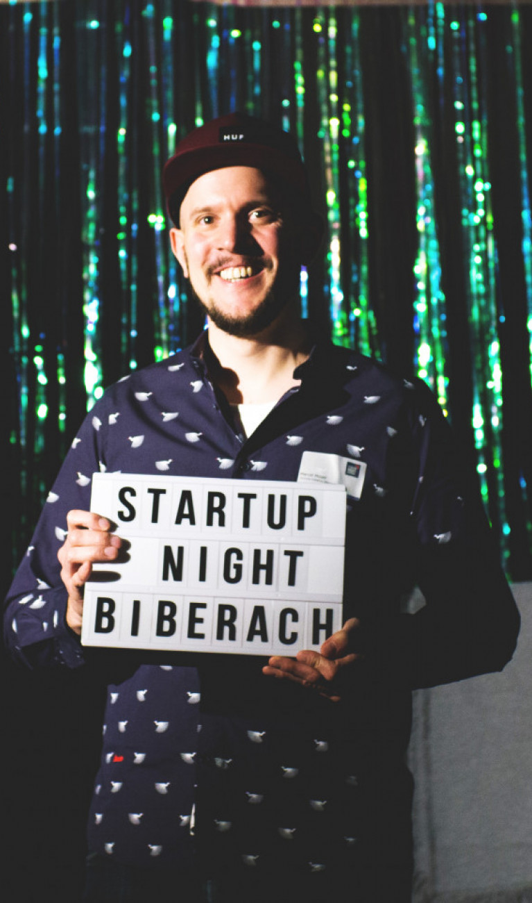 Mann mit Schild und Schriftzug "Startup Night Biberach"