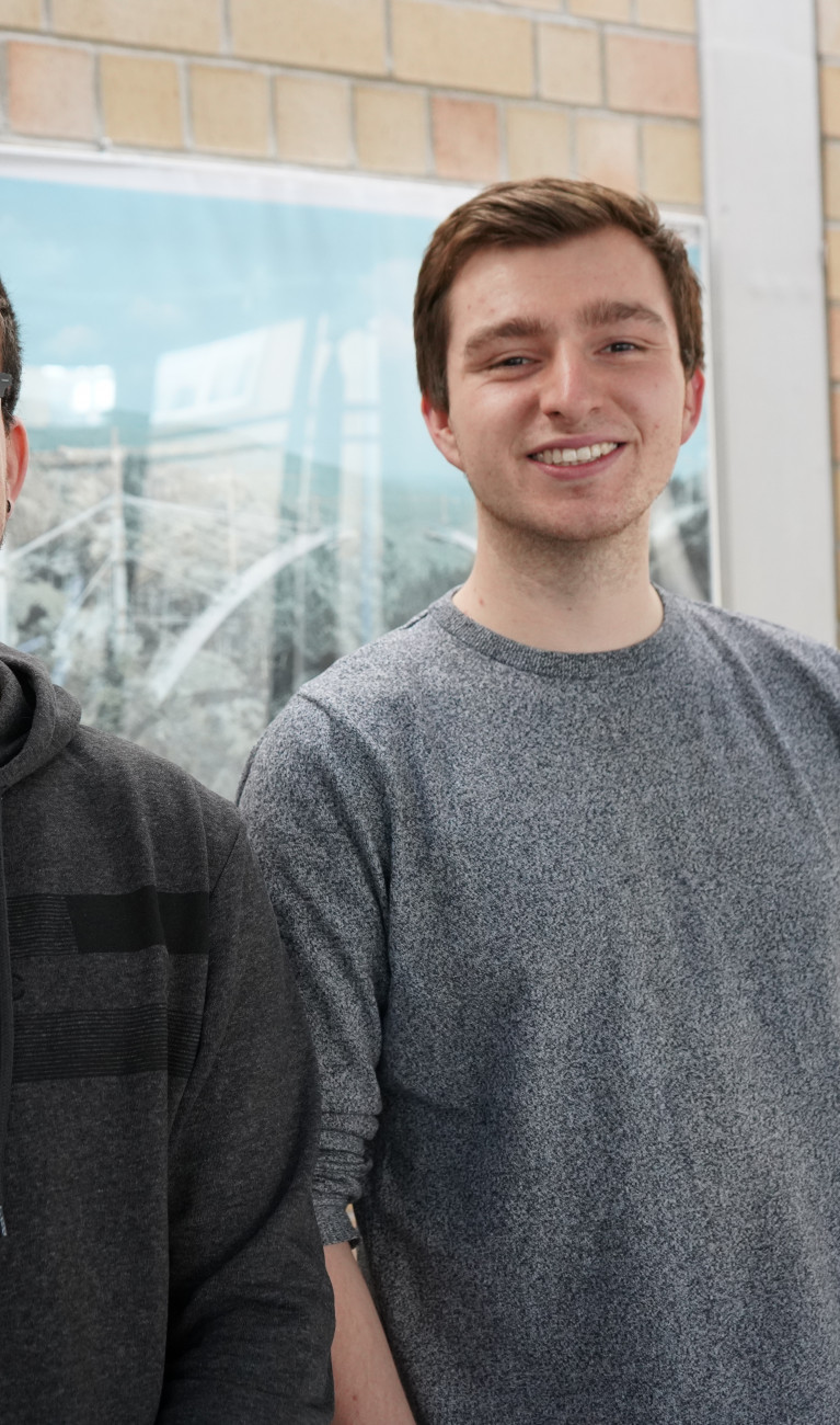 Zwei Studierende stehend vor Wand