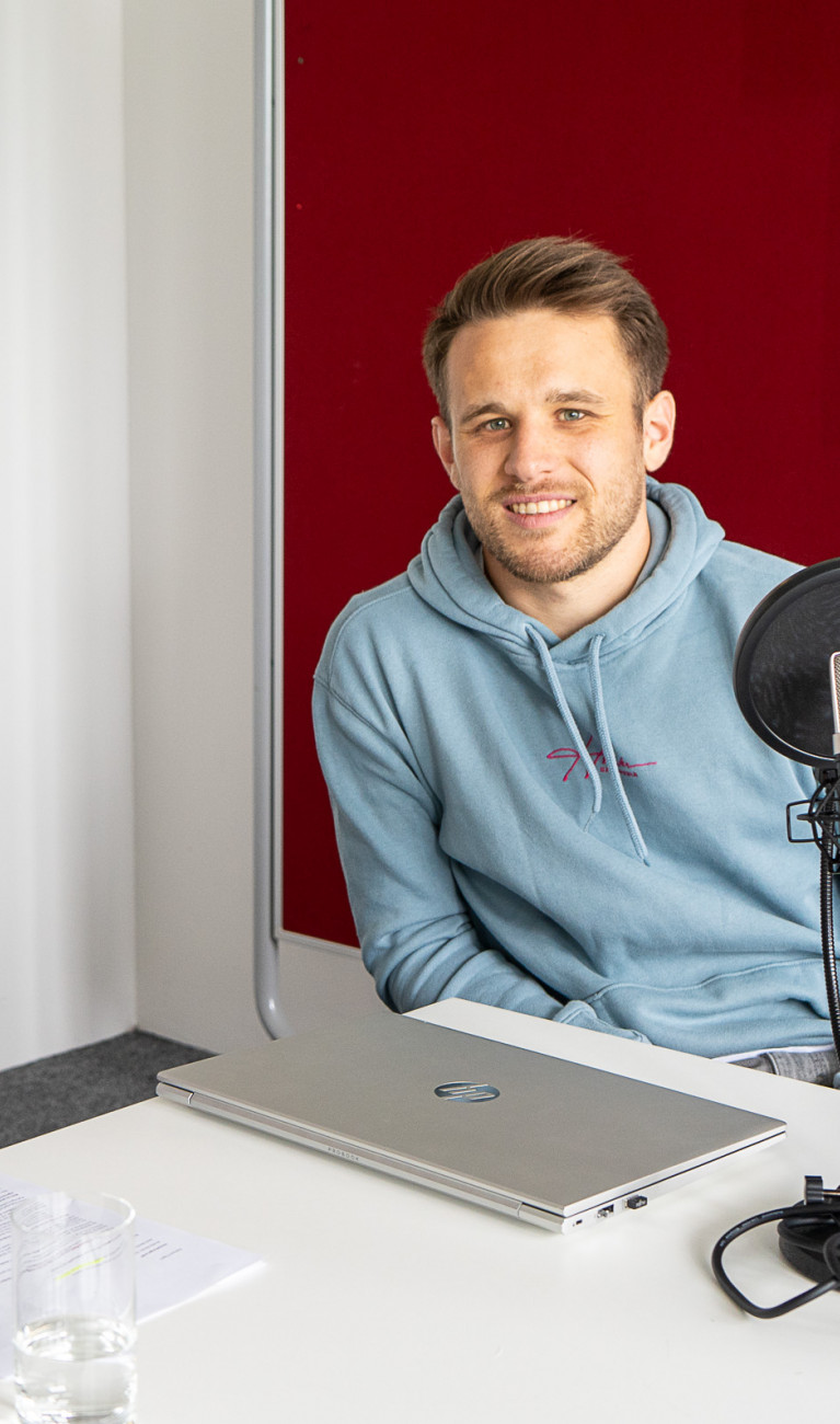 Eine Frau und ein Mann sitzen an einem Tisch und nehmen einen Podcast auf