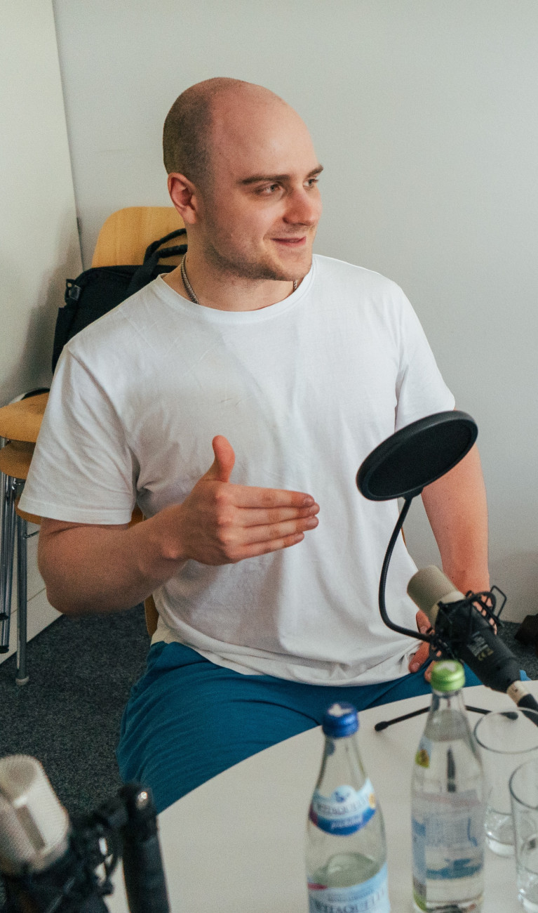 Zwei Männer sitzen an einem Tisch bei einer Podcastaufnahme