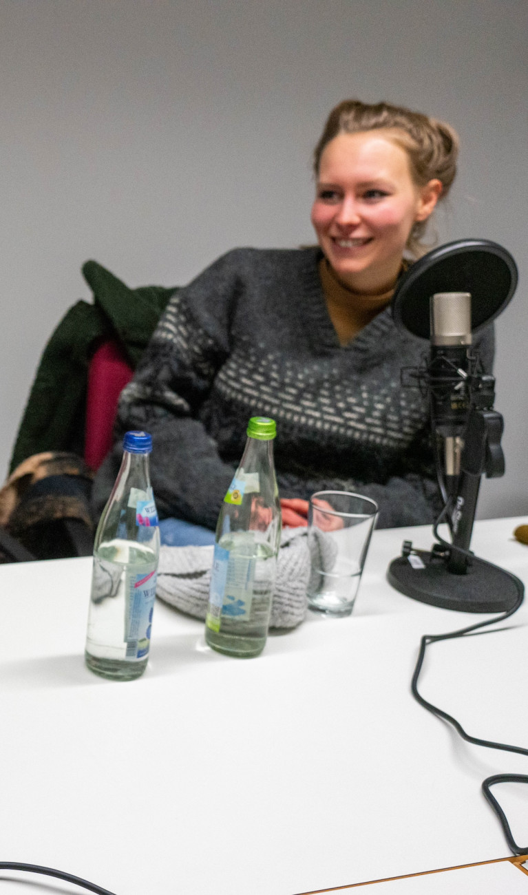 Ein Mann und eine Frau sitzen an einem Tisch bei Podcastaufnahme