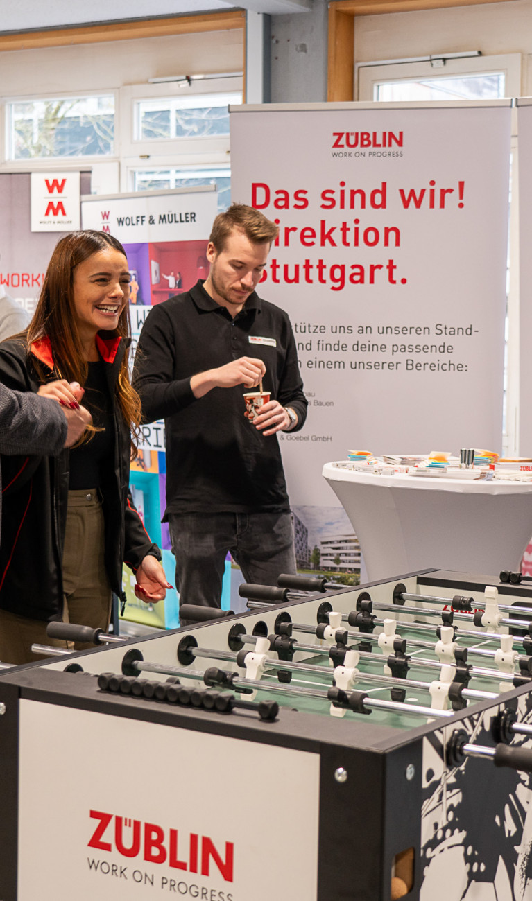 Viele Personen stehen auf einer Messe an einem Kickertisch