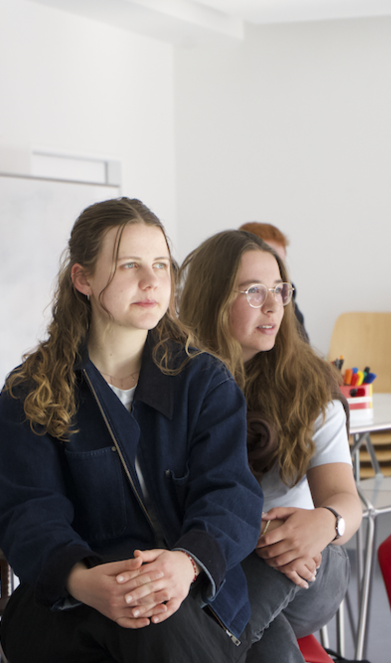 Studierende sitzen an Tischen
