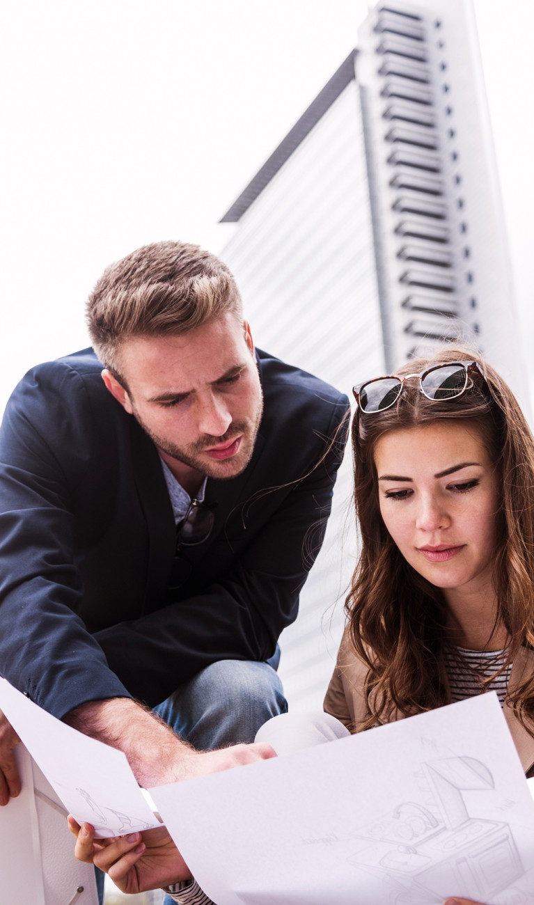Ein Mann und eine Frau halten einen Bauplan