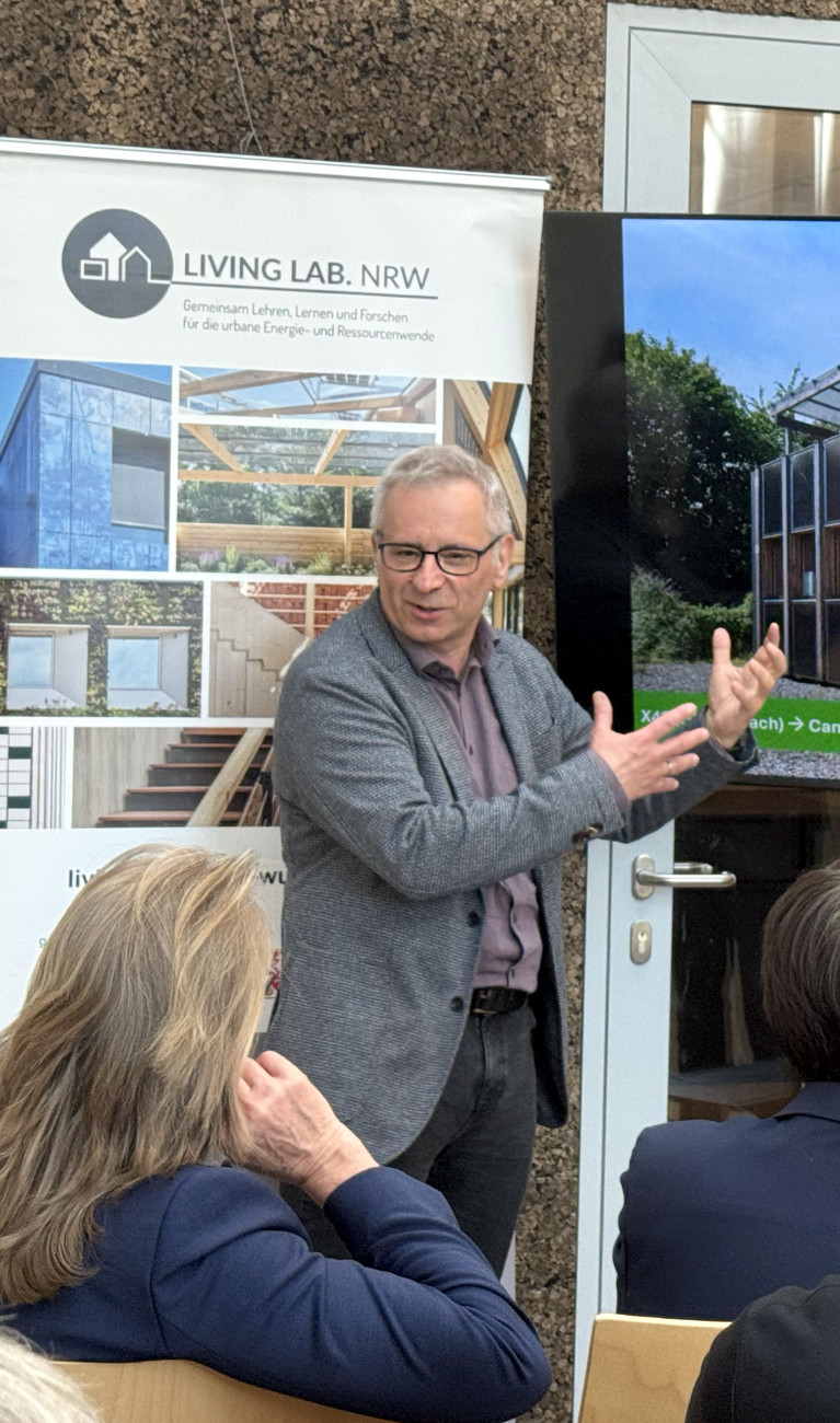 Ein Mann steht vor einem Bildschirm und erklärt etwas