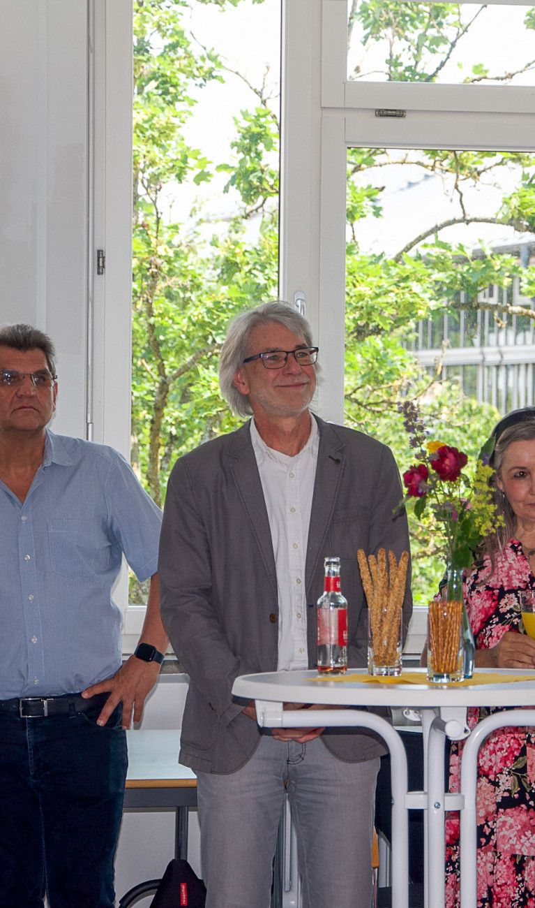 Fünf Erwachsene stehen in einer Reihe bei einer festlichen Veranstaltung