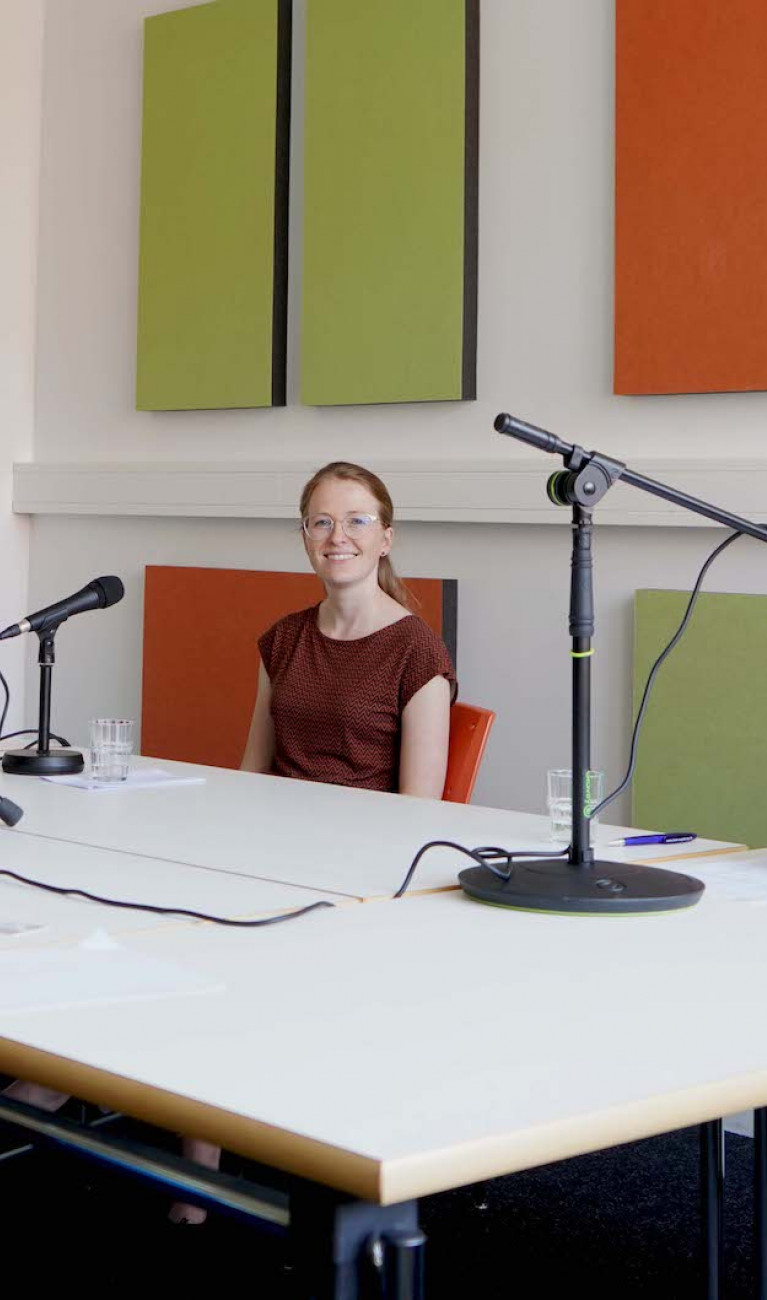 Drei Personen bei Podcastaufnahme an einem Tisch