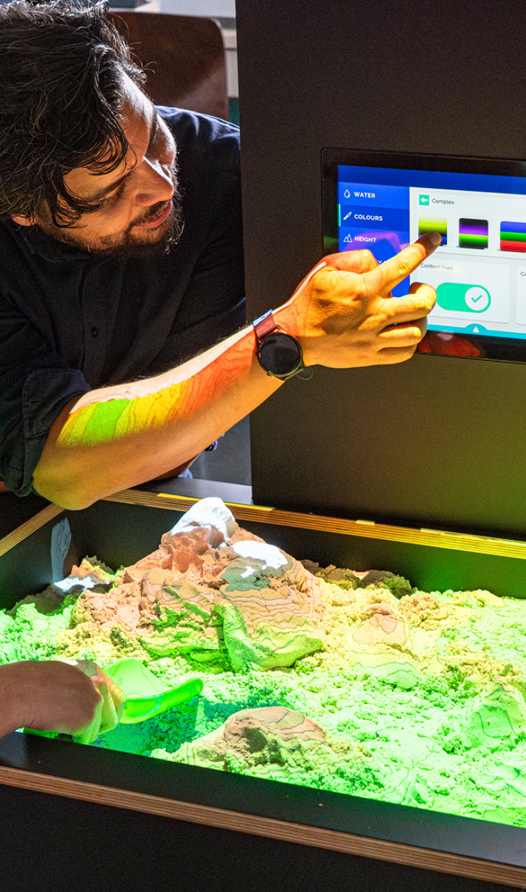 Professor Julius Jara gemeinsam mit zwei Studierenden an der AR-Sandbox