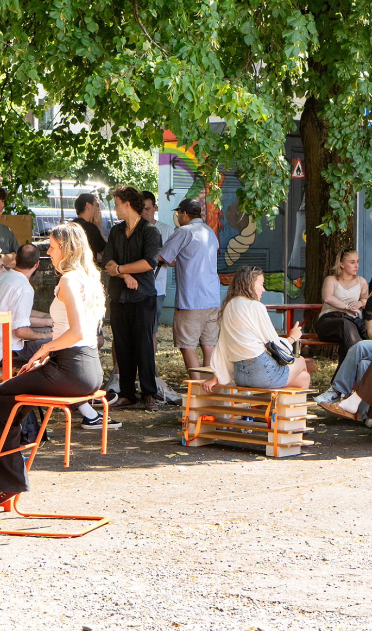 Studierende sitzen an und auf den neuen Möbeln des HBC-Lindengartens