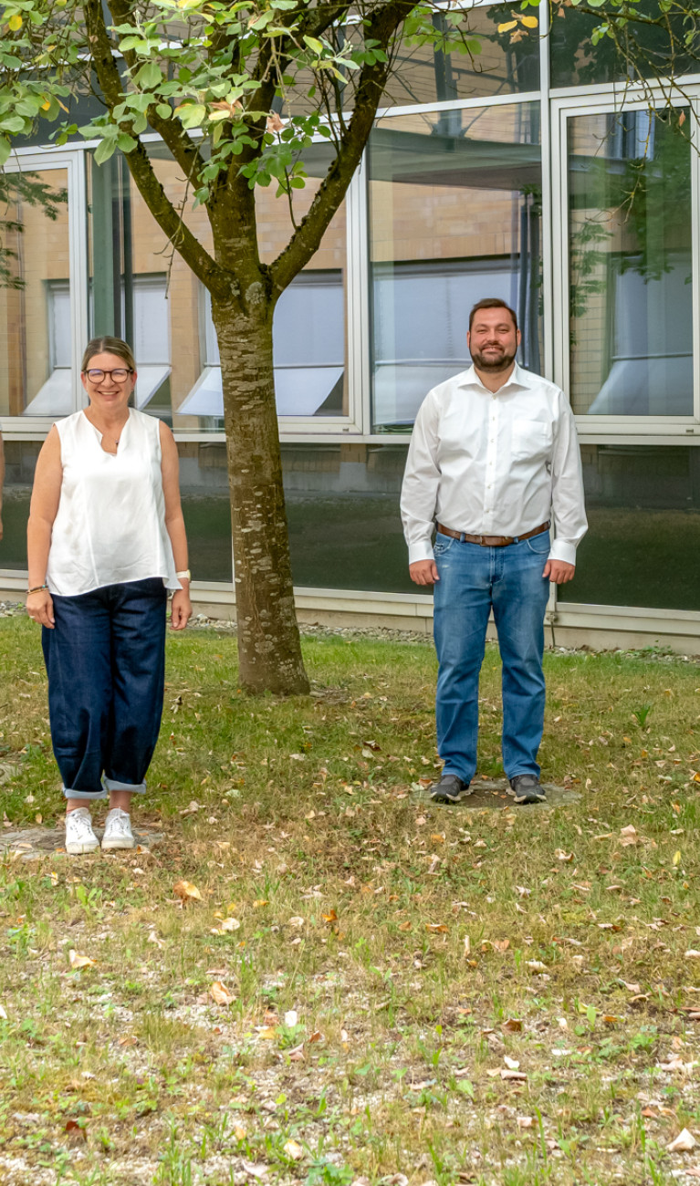 8 Mitarbeiter*innen stehen auf einer grünen Wiese