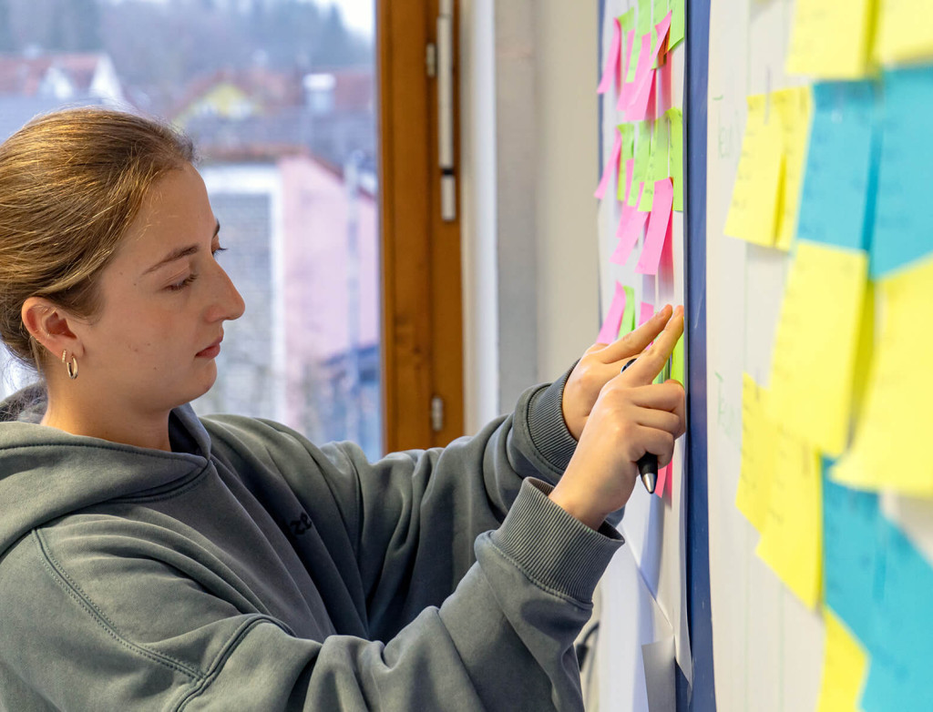 Eine Studierende sortiert Post-Its an der Wand um sich einen Überblick zum Thema SAP zu verschaffen