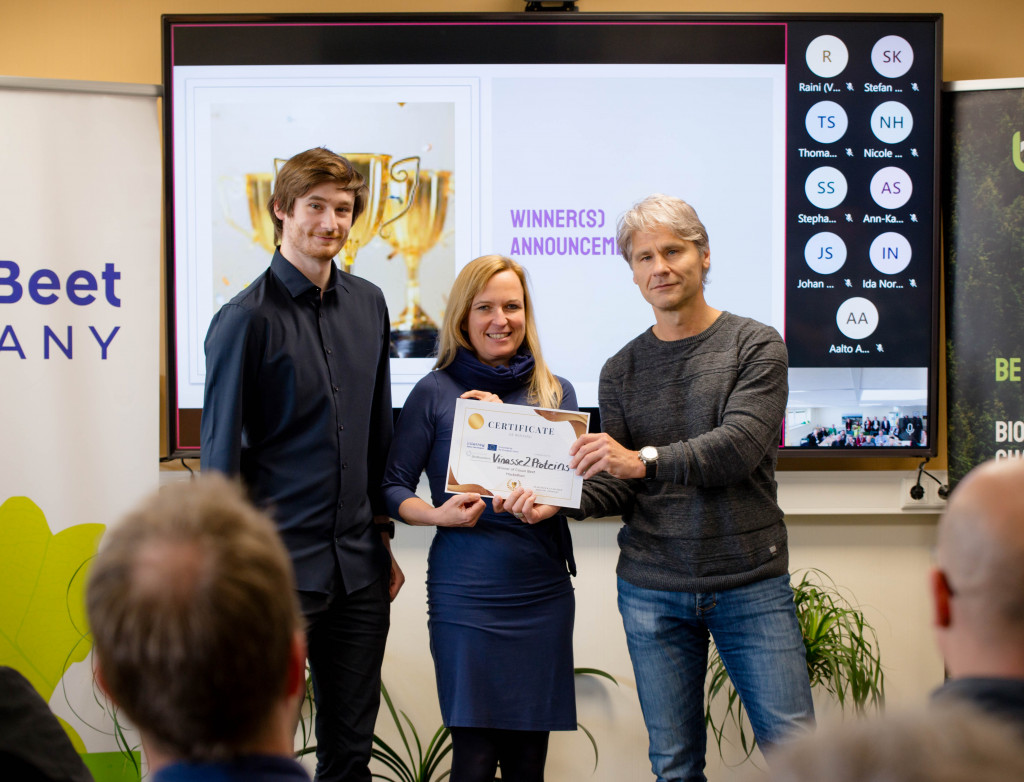 Ein Mann übergibt Urkunde an eine Frau und einen Mann