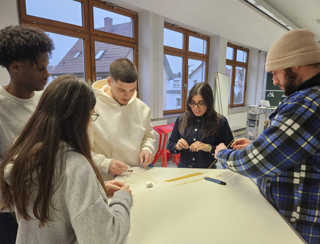 Studierende stehen an einem Tisch und basteln mit Marshmallows