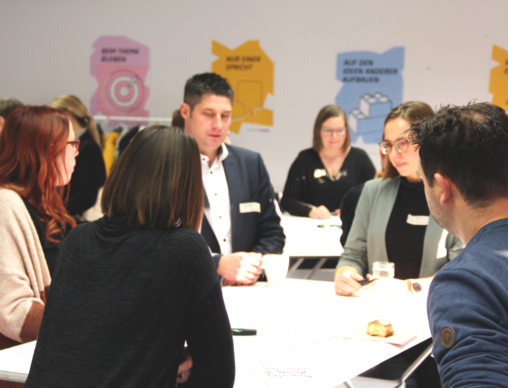 Erwachsene stehen um Tisch herum