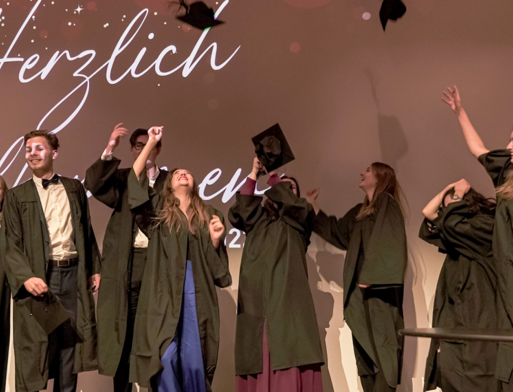 Absolvent*innen werfen Hüte in die Luft