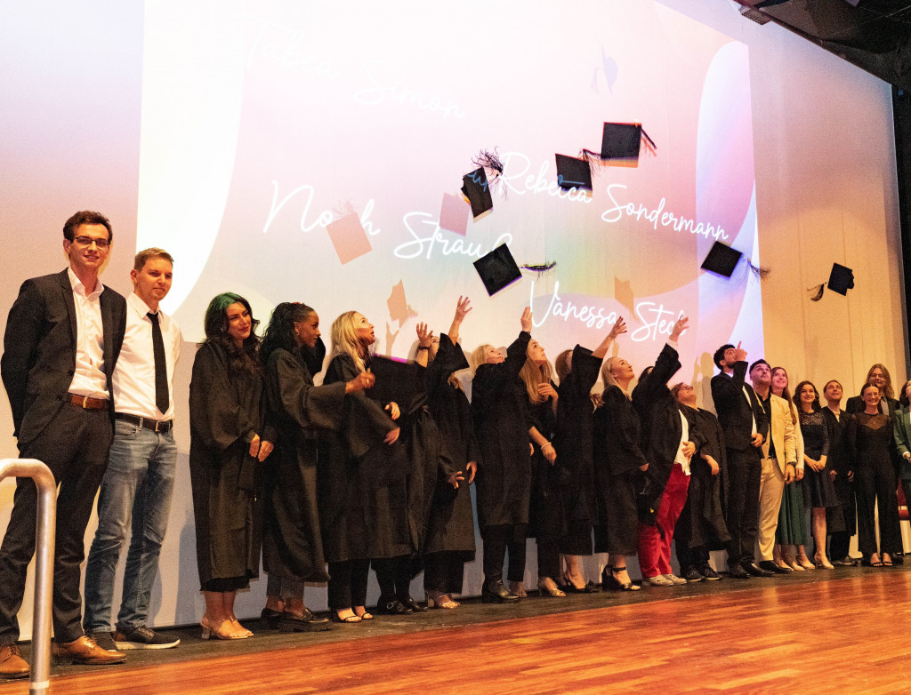 Studierende werfen Absolventenhüte in die Luft