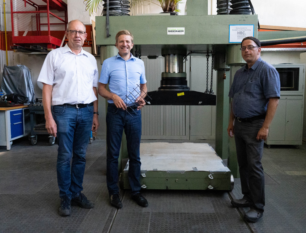 Drei Personen vor Prüfmaschine