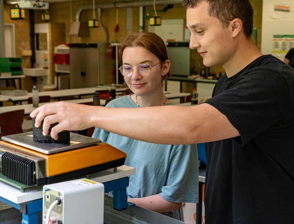 Eine junge Frau und ein junger Mann stehen im Labor für Straßenbau
