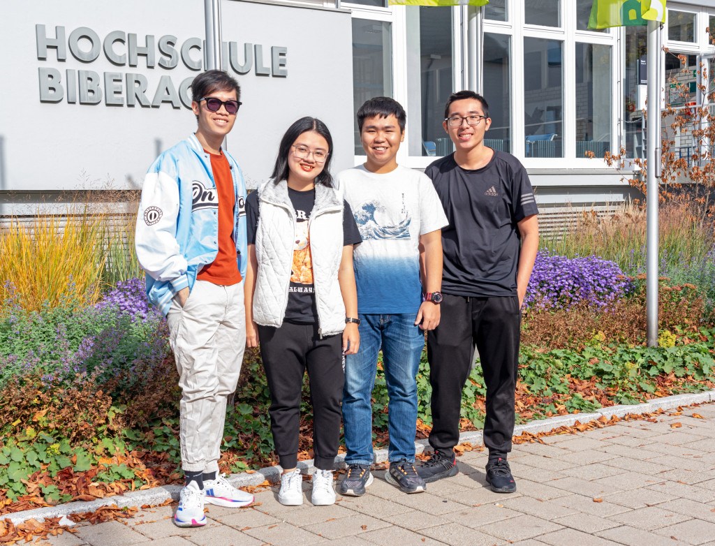 Studierende aus Vietnam stehend vor HBC-Schriftzug