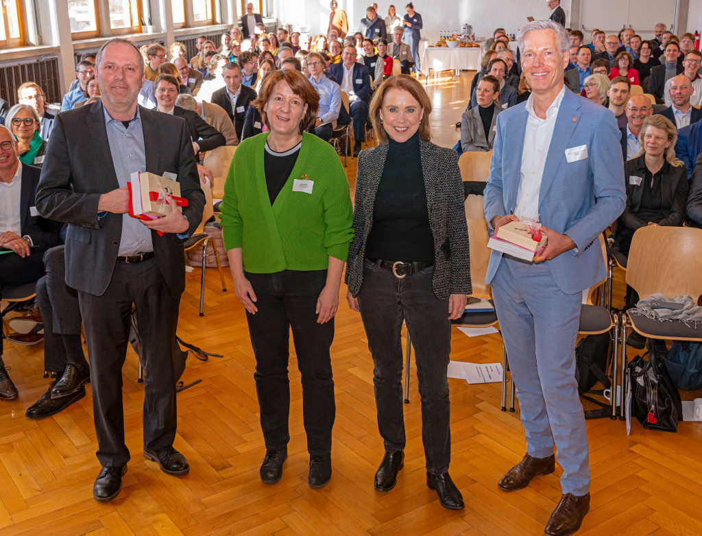 Vier Personen stehen vor großem Publikum