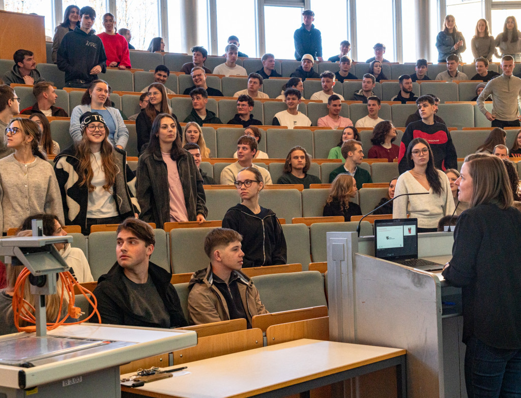 Studierende sitzen und stehen in einem Hörsaal