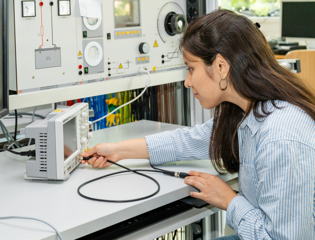 Studentin sitzt an einem Schreibtisch und stellt ein Gerät ein