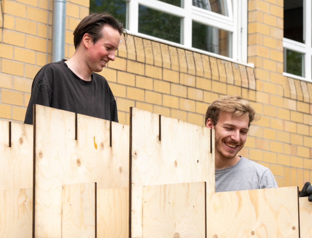 Zwei Studierende bauen ein Pavillon aus Holz auf