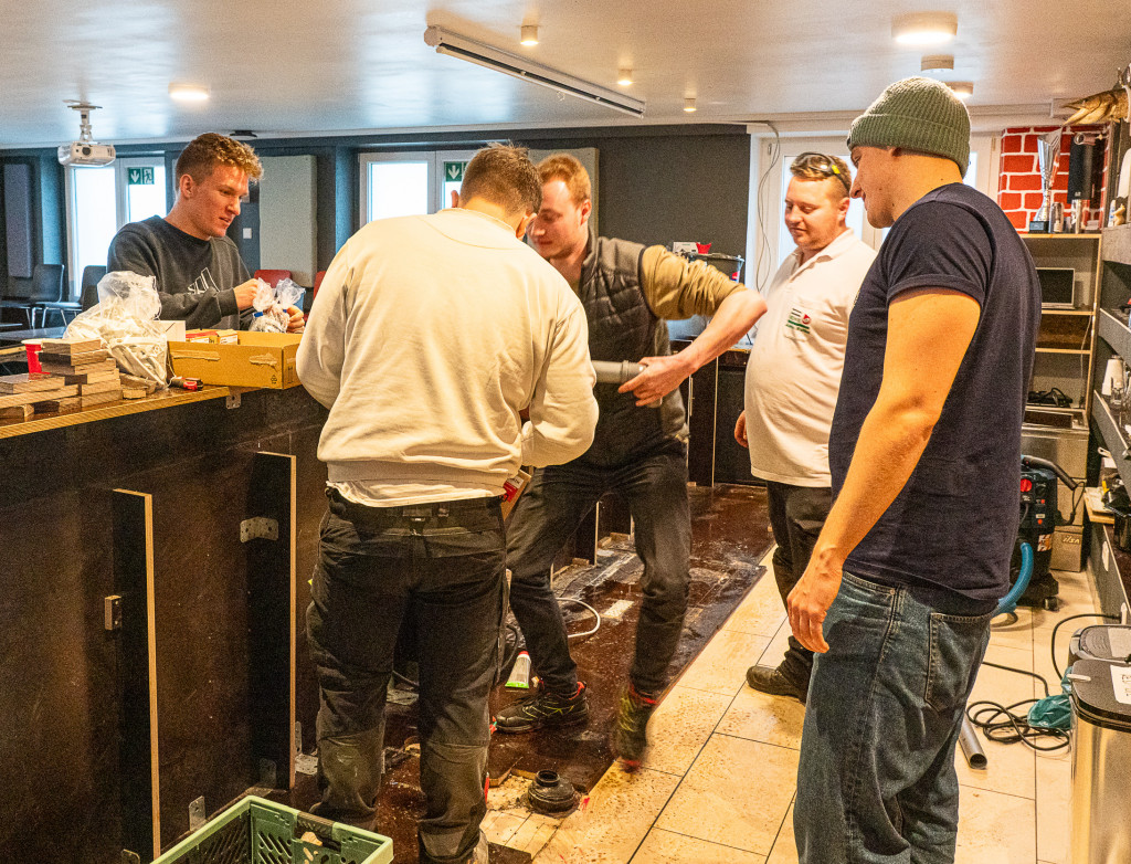 Fünf Männer in einer Kneipe, die die Theke ausbauen