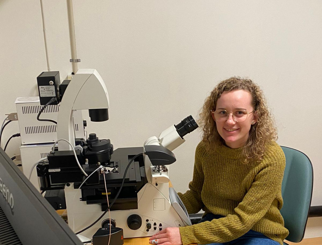 Junge Frau sitzt vor Mikroskop