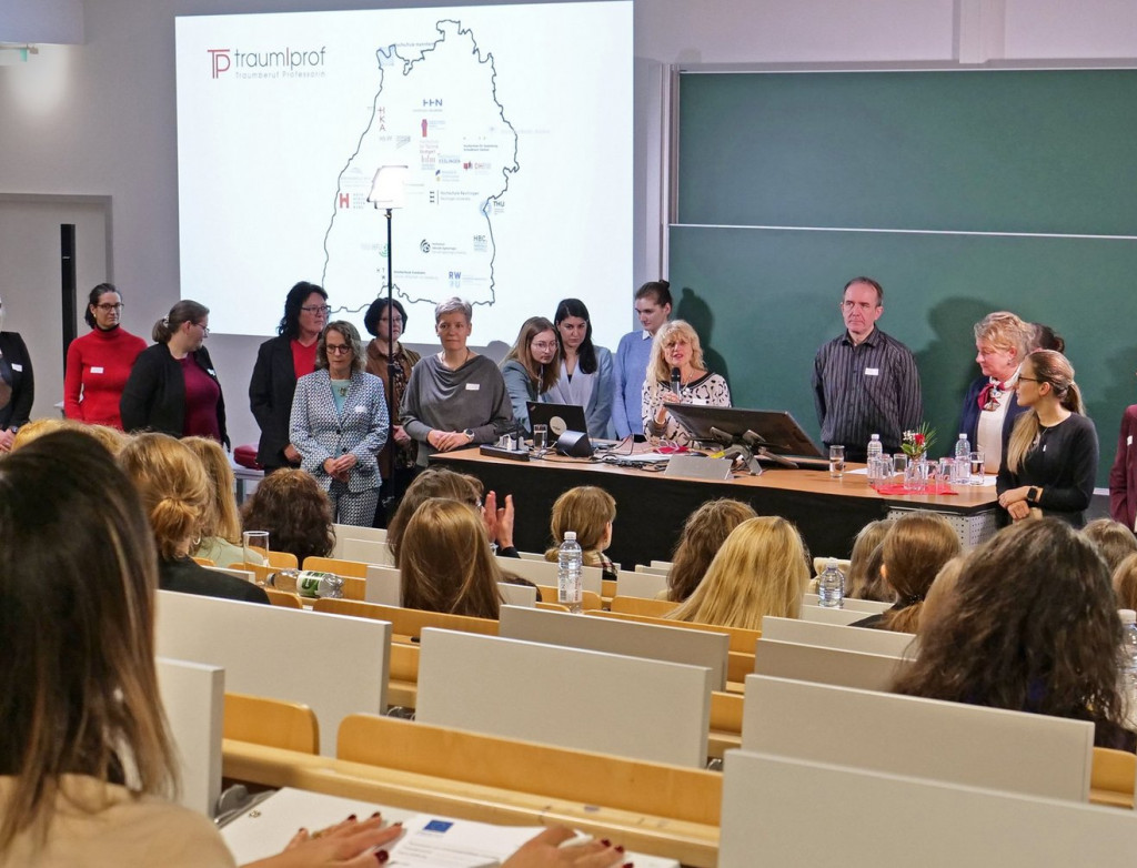 Viele Menschen stehen in Hörsaal vor Tafel