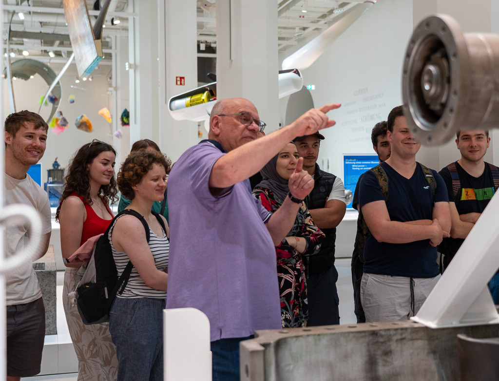 Mann steht im Museum und erklärt etwas