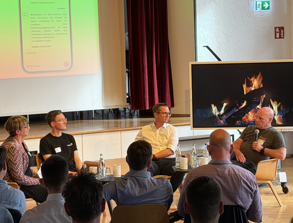 Personen sitzen bei einer Podiumsdiskussion vor Publikum