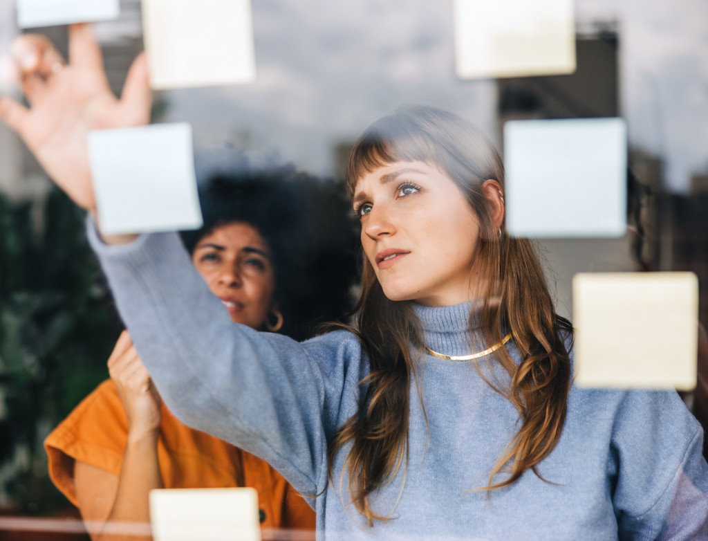 Zwei Frauen kleben Postits auf