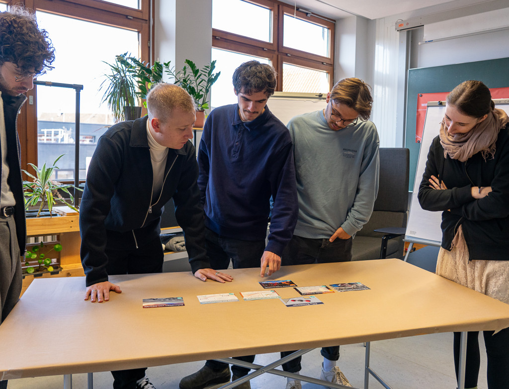 Personen stehen um einen Tisch herum und arbeiten interaktiv