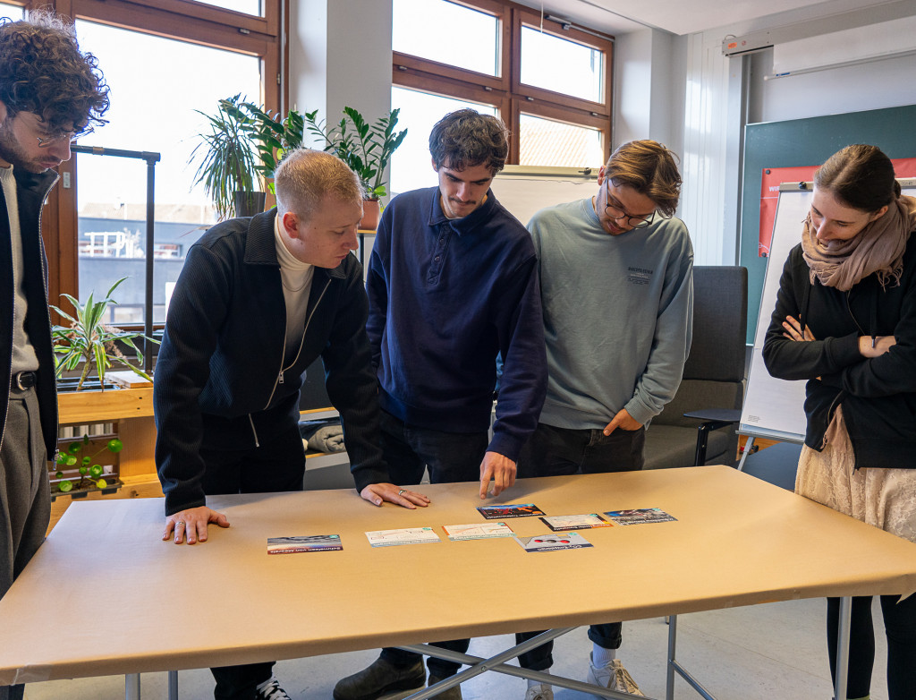 Personen stehen um einen Tisch herum und arbeiten interaktiv