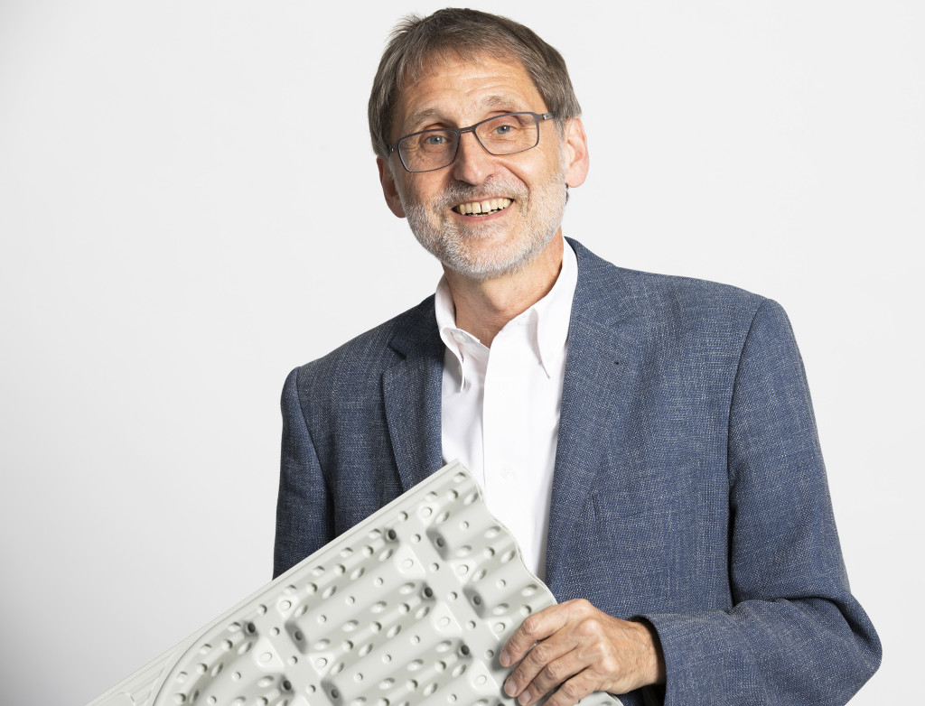 Ein Mann hält etwas in der Hand und lacht in die Kamera