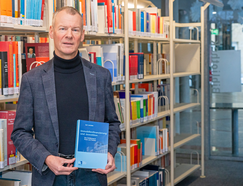 Mann im Bibliothek hält Buch hoch