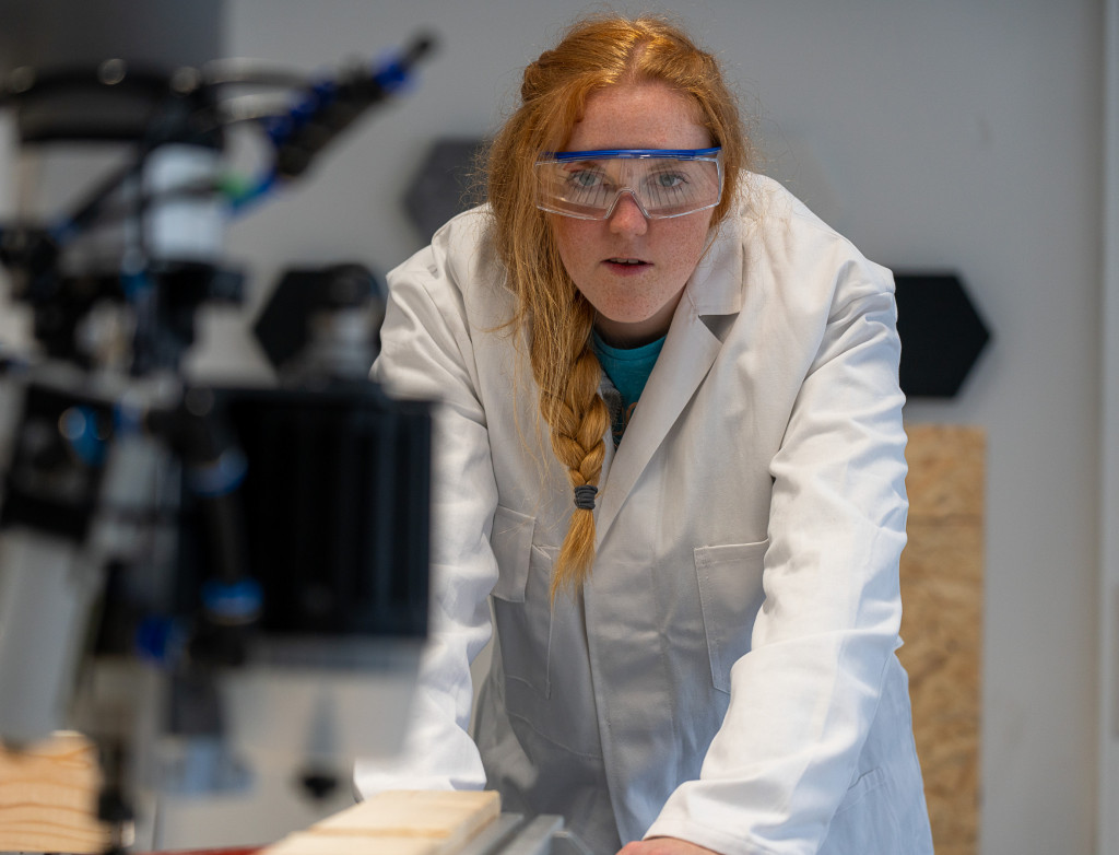 Frau steht vor Roboterarm im Labor