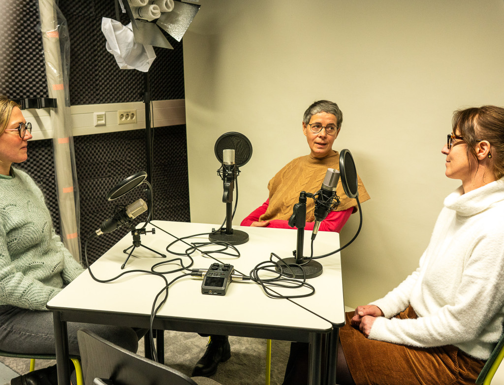 Drei Frauen sitzen bei einem Podcast am Tisch