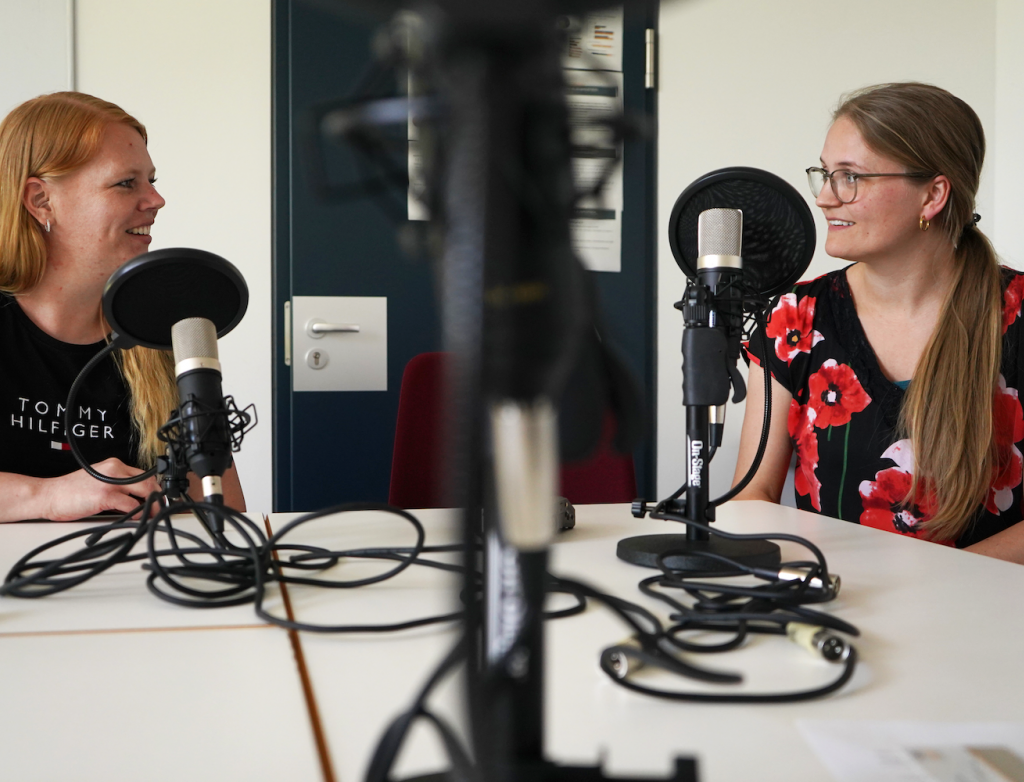 Zwei Frauen sitzen am Mikrofon bei Podcastaufnahme