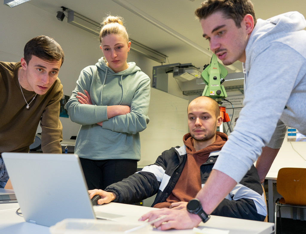 Vier Studierende arbeiten an einem Laptop