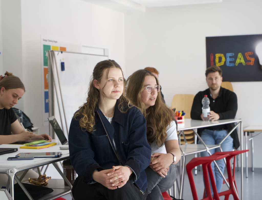 Studierende sitzen an Tischen