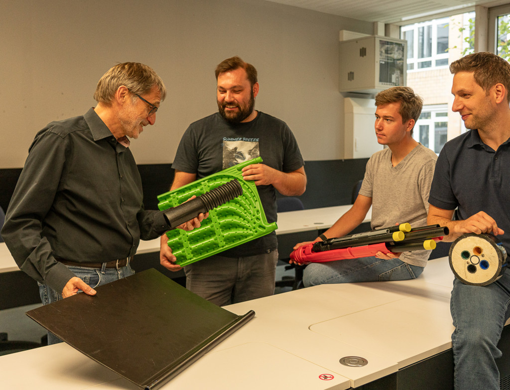 Vier Männer zeigen technisches Material