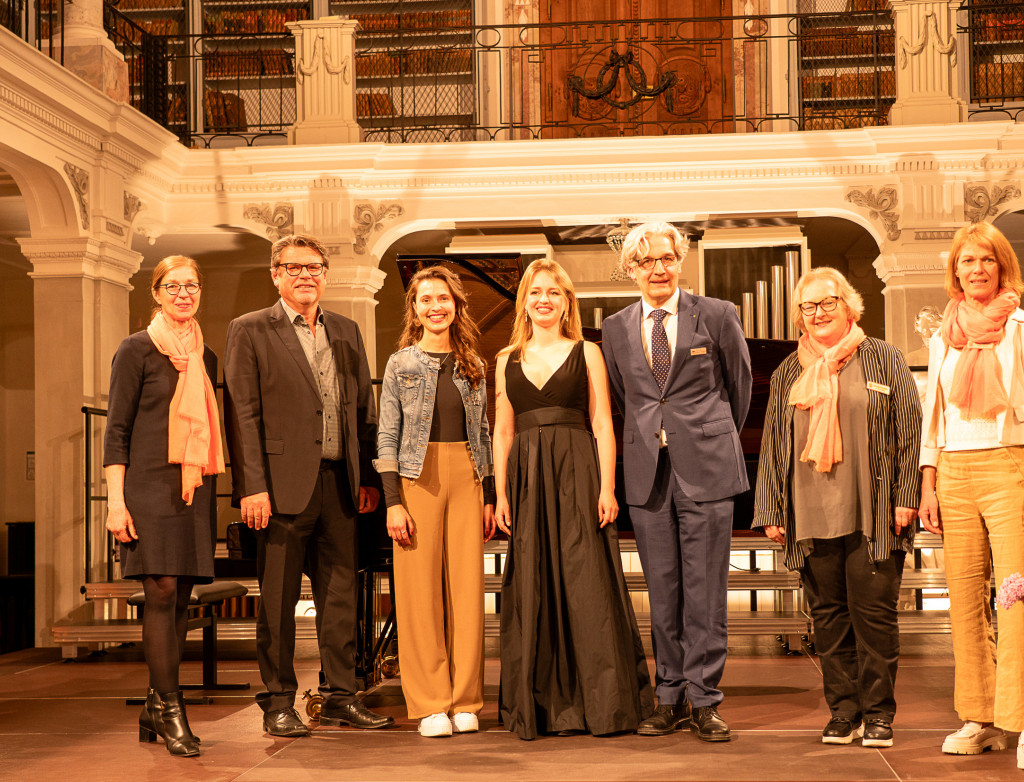 7 Personen stehen auf einer Bühne