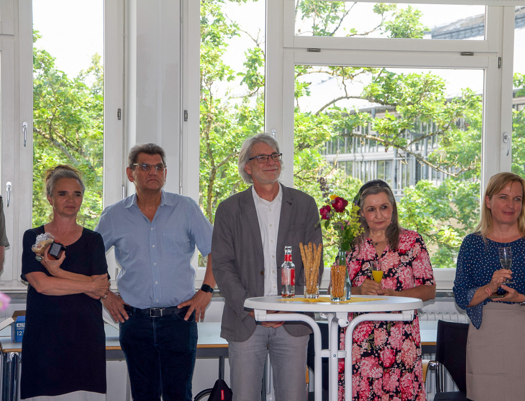 Fünf Erwachsene stehen in einer Reihe bei einer festlichen Veranstaltung