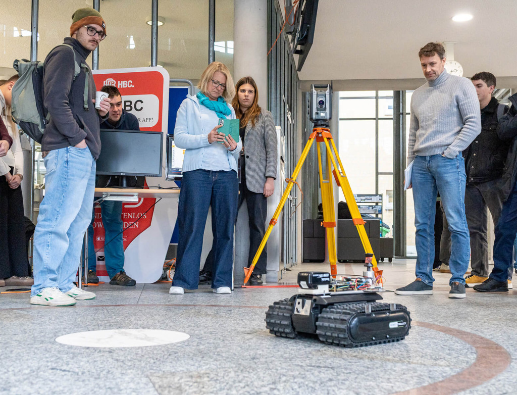 Eine Gruppe Studierender und Professor*innen steuert und filmt einen autonomen Roboter für die Baustelle